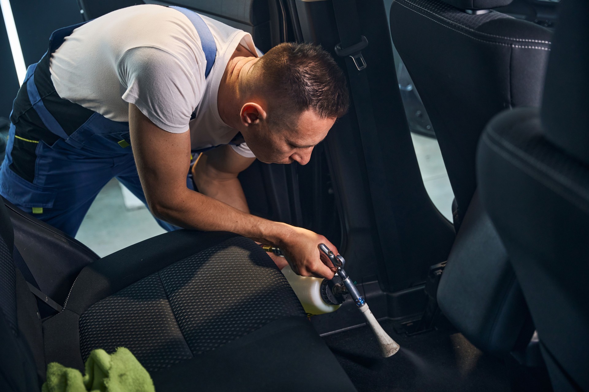 Worker thoroughly cleans the interior of a car using steam